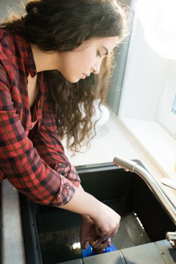Woman cleaning clogged drain