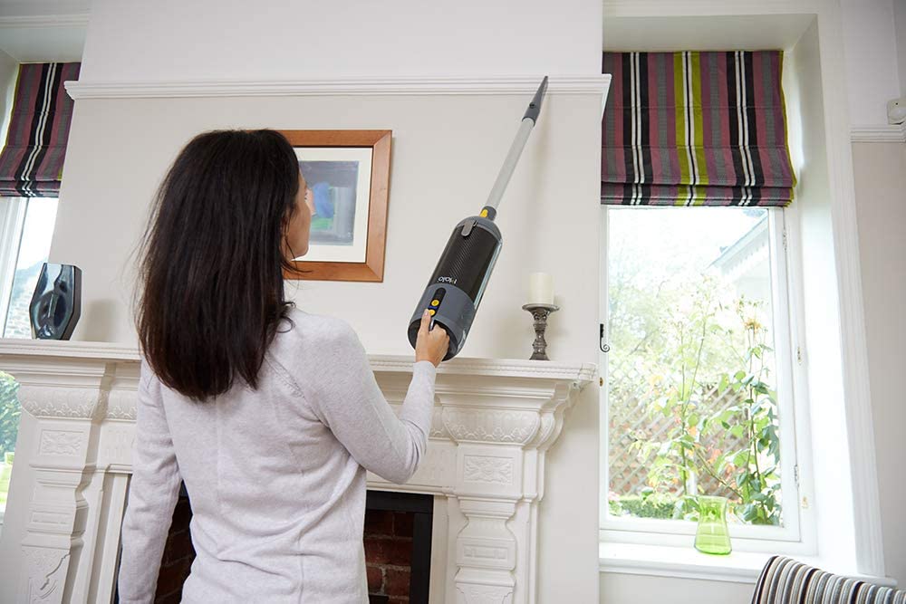 Lady cleaning high with handlheld vacuum cleaner